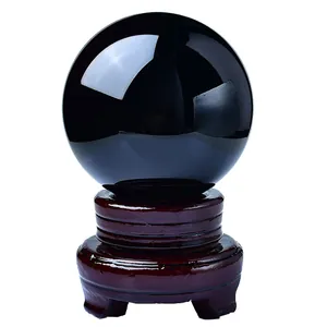 Polished black obsidian crystal ball on a vintage carved wooden display stand