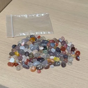 Polished colorful natural agate stones scattered on a light wood surface in a clear bag