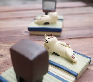 Detailopname van een Japans kattenbeeldje op een mat naast een vintage televisie-model