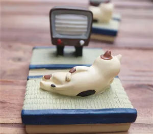 Detailopname van een lapjeskat op tatami met een mini vintage TV als telefoonhouder