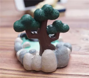 Detailopname van een miniatuur bonsai boom van hars met realistische stenen op de basis