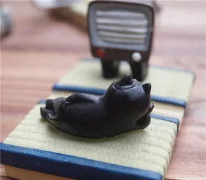 Macro-opname van zwart kattenbeeldje op mini tatami-mat als creatieve telefoonhouder