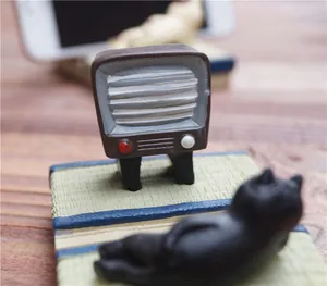 Close-up van een miniatuur retro TV en slapende zwarte kat op een groene tatami-mat