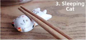 Macro shot of cute ceramic calico cat chopstick rest in sleeping pose on wooden desk