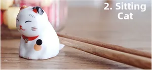 Macro shot of a cute ceramic lucky cat chopstick rest in a lying posture with wooden chopsticks