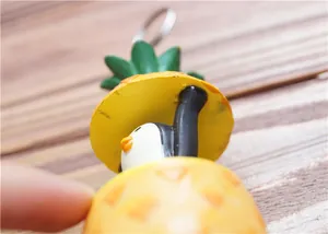 Nahaufnahme des Ananas-Pinguin-Anhängers mit Metallring auf hellem Holzgrund