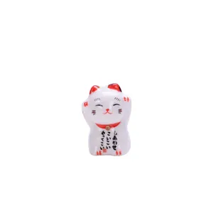 Cute Japanese ceramic lucky cat figurine with raised paws and golden bell on white background