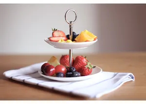 Detailed view of a 2-tier ceramic cake stand with white porcelain plates and silver handle