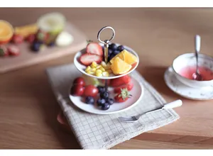 Close-up of double tier white ceramic cake stand with fruit on a wooden table