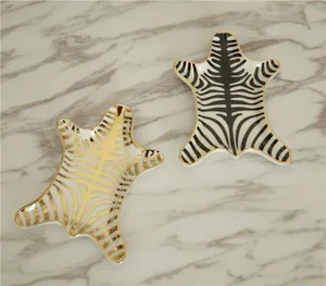 Close-up of zebra pattern ceramic jewelry trays with elegant gold edges in two colors