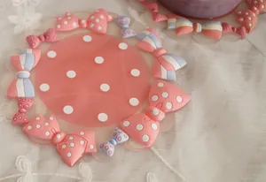 Cute pink PVC coaster with white polka dots and 3D bow accents on lace fabric