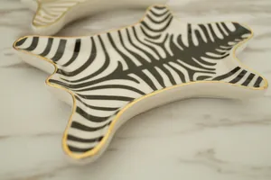 Close-up of zebra pattern ceramic jewelry tray with elegant gold-rimmed edges