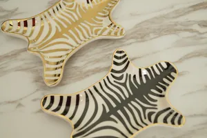 Detailed view of two ceramic zebra patterned jewelry trays with elegant gold edges