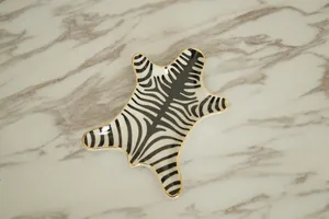 Detail view of zebra print ceramic jewelry tray with gold edge on marble surface