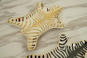Detailed close-up of ceramic jewelry tray featuring gold zebra print and animal skin pattern