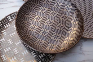 Artistic caramel gold ceramic plates set with geometric embossed patterns on marble