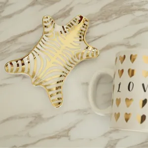 Zebra pattern ceramic jewelry tray with gold plating and white love mug on marble
