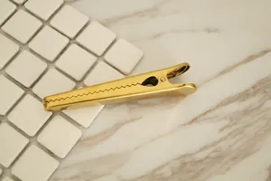 Macro detail of large gold brass clip with matte finish and jagged teeth design