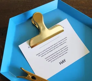 Close-up of golden stainless steel metal binder clips on a blue decorative tray