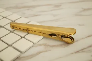 Golden stainless steel large coffee bag sealer clip on a marble surface with keyboard