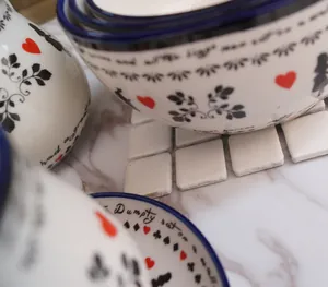 Macro-opname van keramisch servies in sprookjesstijl met rode harten en zwarte ranken