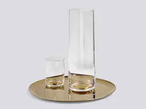 Minimalist gold round metal tray holding premium glassware on a grey background