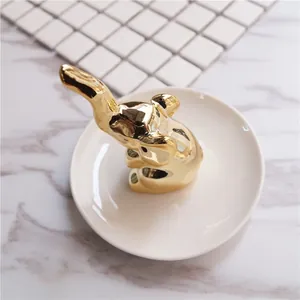 Golden elephant jewelry holder on white ceramic tray for ring and necklace storage