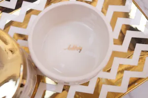 White ceramic trinket jar with golden lid and 'happy' inscription inside the bowl