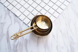 Vue détaillée d'une tasse à mesurer dorée en inox avec graduations de 1/4 Cup et 60 ml