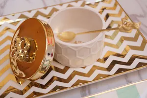 Detail of white honeycomb ceramic jar with gold lid and bear handle spoon set