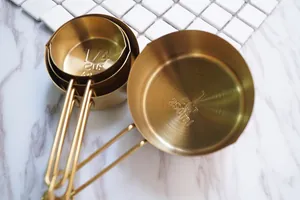 Gravure détaillée des unités 60ml et 250ml sur les tasses à mesurer dorées en acier