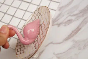 Détail du plateau à bijoux flamant rose en céramique avec motif à carreaux dorés et bords
