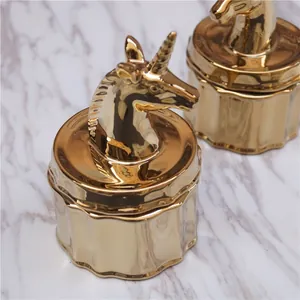 Detailed top view of gold-plated unicorn ceramic jewelry boxes on marble background