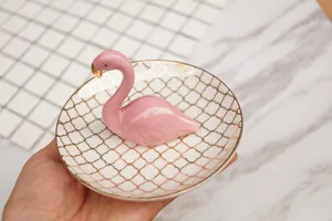 Gros plan d'un plateau à bijoux en céramique avec flamant rose et motifs trèfles dorés