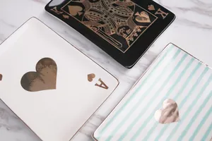 Overhead view of ceramic poker-themed jewelry trays with gold edges on marble