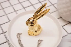 Golden rabbit ceramic jewelry holder on a white tray with earrings on tiled background