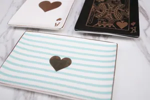 Ceramic poker-themed jewelry trays with gold trim on a minimalist marble background