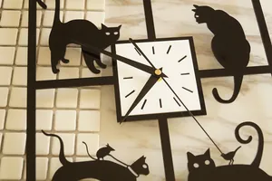 Detaillierte Nahaufnahme der quadratischen Wanduhr mit spielerischen schwarzen Katzen-Silhouetten