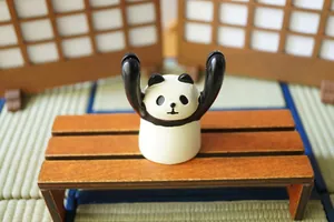 Cute panda resin desktop stand holding up arms for card or glasses on wooden bench