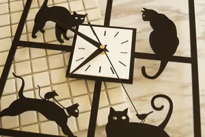 Detailansicht der minimalistischen Wanduhr mit Katzensilhouetten und weißem Zifferblatt