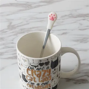 Cute stainless steel stirring spoon with a pink 3D cat paw silicone handle in white mug