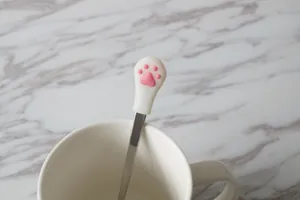 Macro view of stainless steel coffee spoon with pink 3D cat paw handle detail