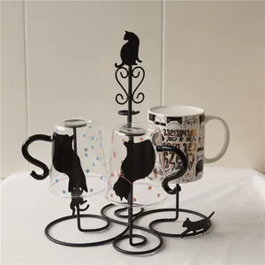 Close-up of black iron cat-themed cup holder with polka dot glass and ceramic mug