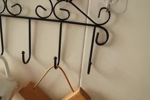 Close-up of black iron cat wall hook with U-shaped design on white tile surface