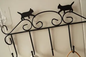 Detail of a vintage black iron wall hook featuring two playful cat silhouettes for home
