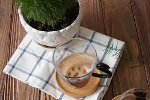Close-up of a glass cup with blue dots on a natural wood cat paw coaster