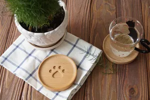 Macro view of a natural wood coaster with an engraved cat paw pattern on a plaid fabric
