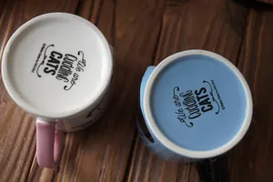 Ceramic cat mugs in pink and blue with Cuddling Cats text on wooden background