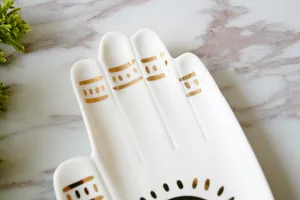 Hamsa hand keramische sieradenschaal met gouden zonpatronen op marmeren blad