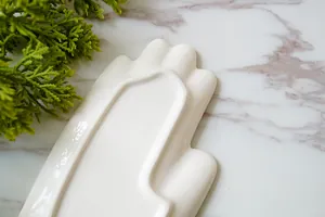 Creatieve handvormige witte keramische sieradenschaal met zontotem op marmer
